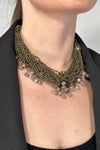 Model is wearing a short multi strand necklace that has extra small and medium sized beads. 