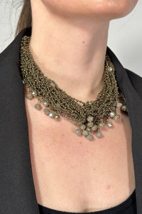 Model is wearing a short multi strand necklace that has extra small and medium sized beads. 
