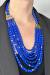 Model is wearing a layered statement necklace with different sized cobalt blue beads. 