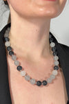 Model is wearing a collar length beaded necklace. 