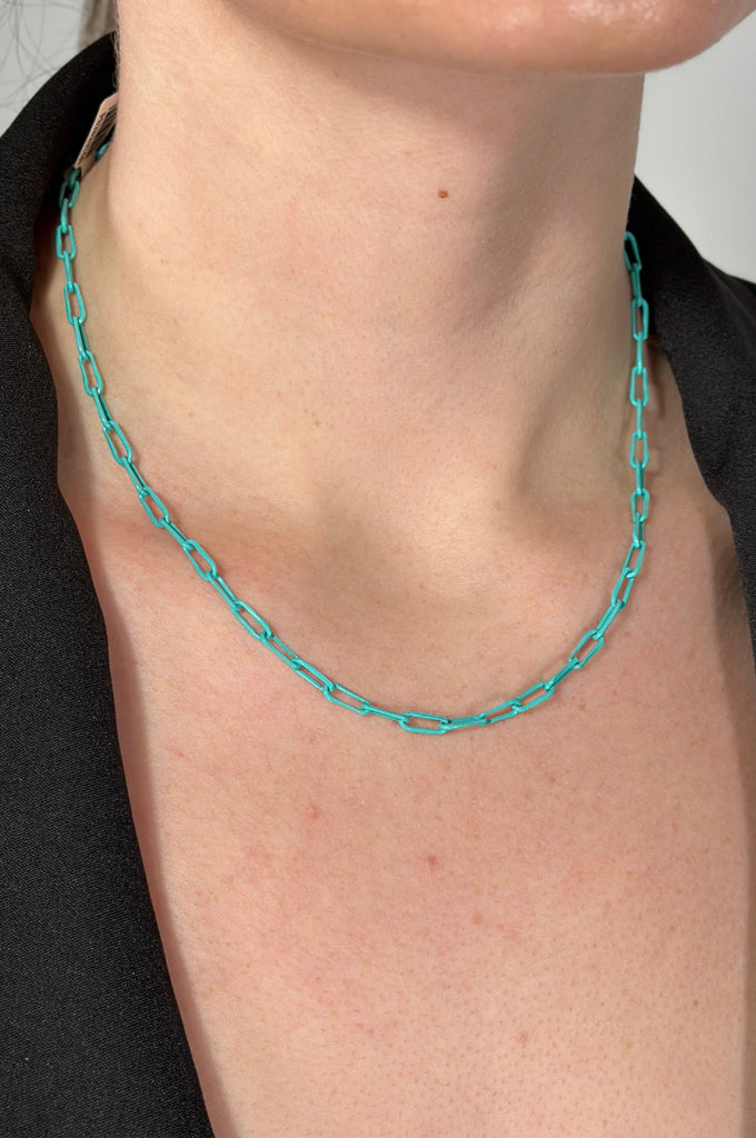 Model is wearing a short turquoise colored paper clip chain necklace.