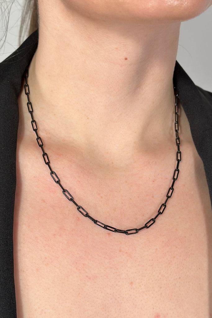 Model is wearing a small black paper clip chain link necklace.