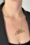 Model is wearing a collar length gold necklace with a mountain charm.