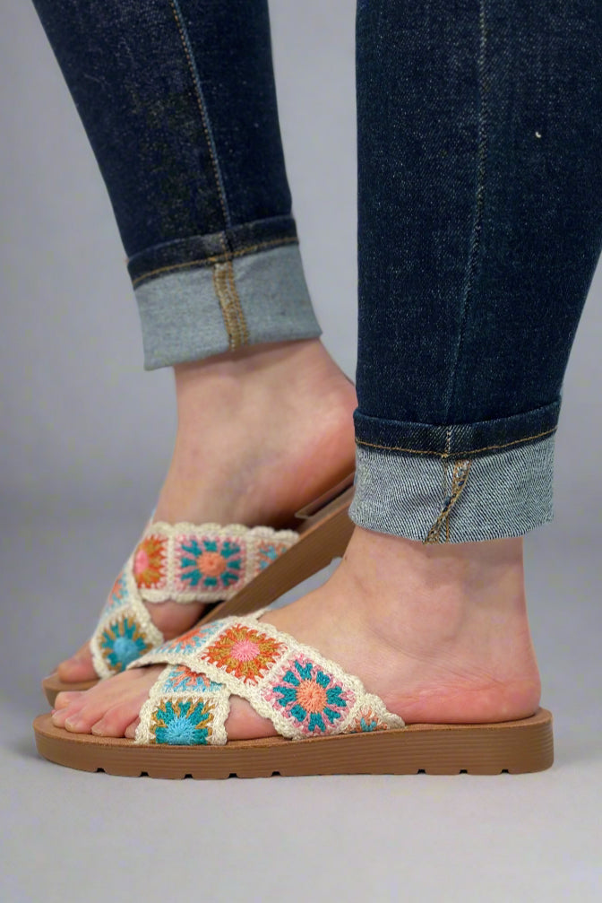 Women’s slip on sandals with colorful crocheted granny square criss-cross strap over foot.