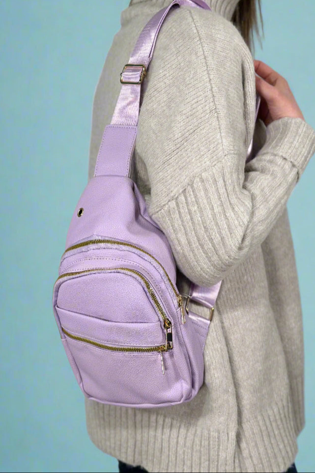 A lilac color, faux leather sling bag with an adjustable strap.