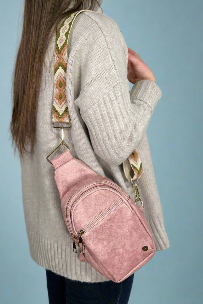 Women’s dusty pink sling bag with zipper closures and removable adjustable embroidered strap.