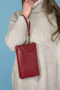 Small faux leather, 3 compartment bag in red with zipper closure and removable wristlet and adjustable crossbody straps.