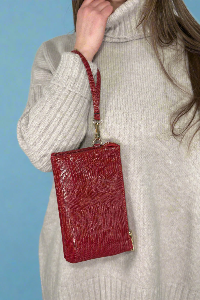 Small faux leather, 3 compartment bag in red with zipper closure and removable wristlet and adjustable crossbody straps.