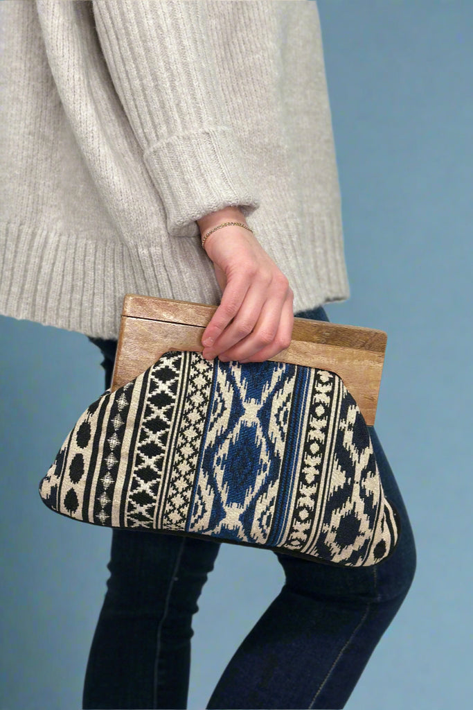 Women’s clutch bag with navy, black, and ivory tribal print and wooden handle closure.