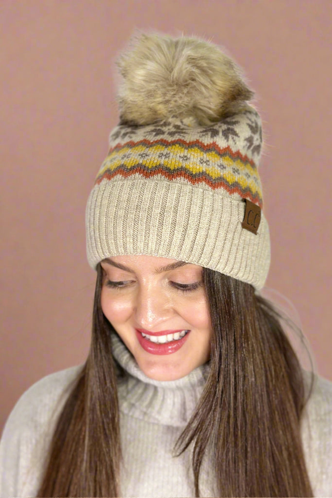 Women's knit beanie with faux fur pom in beige and nordic fair isle print in orange and yellow.