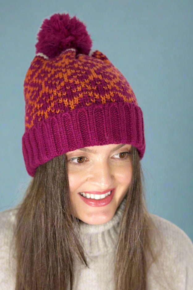 Model is wearing a patterned knit beanie with a pom pom. 