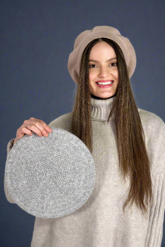 Model is wearing a taupe colored beret and holding up a grey beret to showcase the other color. 