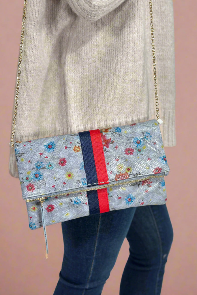 Model is wearing a floral print crossbody bag that doubles as a clutch.