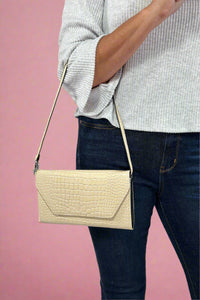 Model is holding a glossy faux snakeskin 3-in-1 clutch purse.