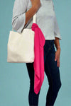 model is showing off a satin hot pink colored scarf tied on a purse. 