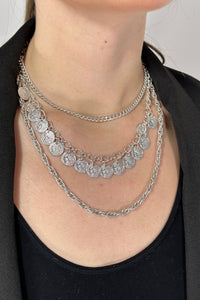 Model is wearing a silver triple chain necklace with silver coins.
