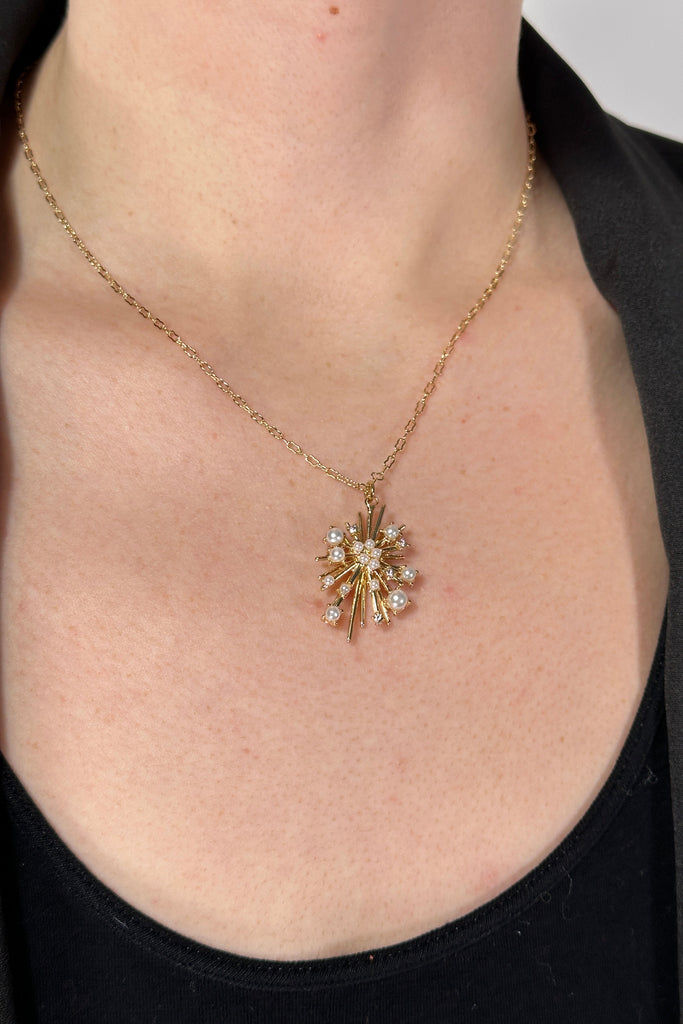 A short necklace in gold plated brass with pearl and cz starburst pendant.