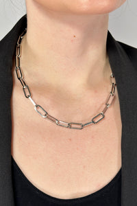 Model is wearing a silver paper clip style chain necklace that is collar length.