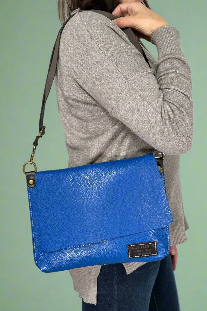 Genuine Italian leather fold-over flap bag in vibrant cobalt blue with detachable adjustable strap for crossbody or shoulder wear.