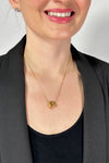 Model is wearing a gold medium length necklace with three small oval shaped pendants. 