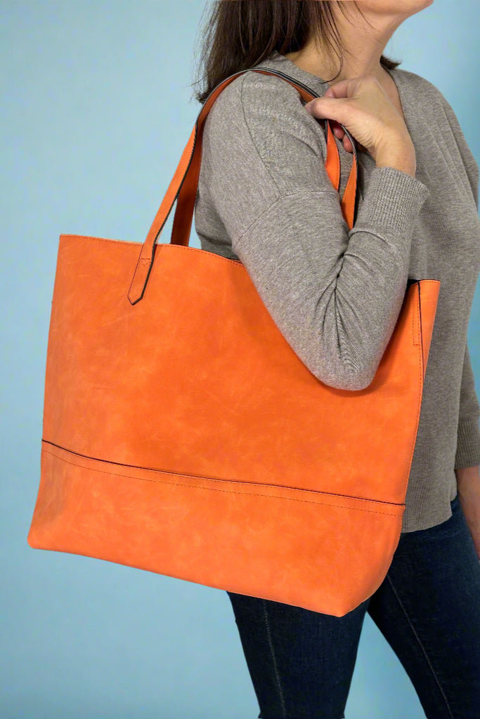 Women’s large tote bag in orange faux suede with open top and RDIF protected card slots inside.