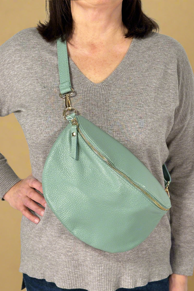 Women’s Italian leather crossbody bag in light sage color with zipper closure and detachable adjustable strap for crossbody or shoulder wear.