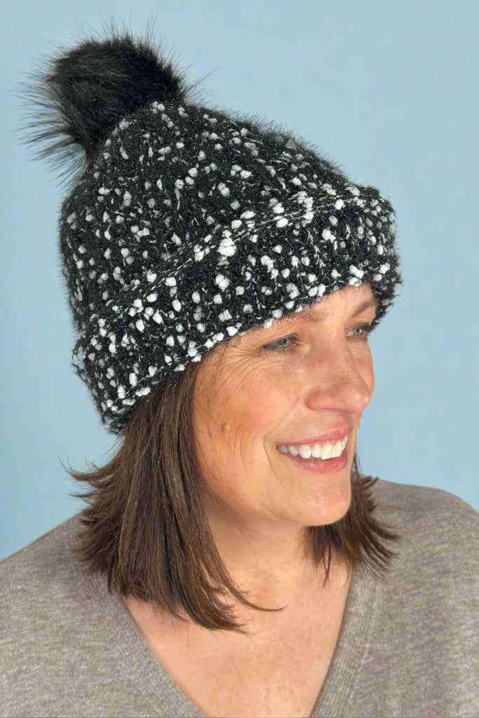 Women's knit winter beanie in black and white speckled knit with black pom.