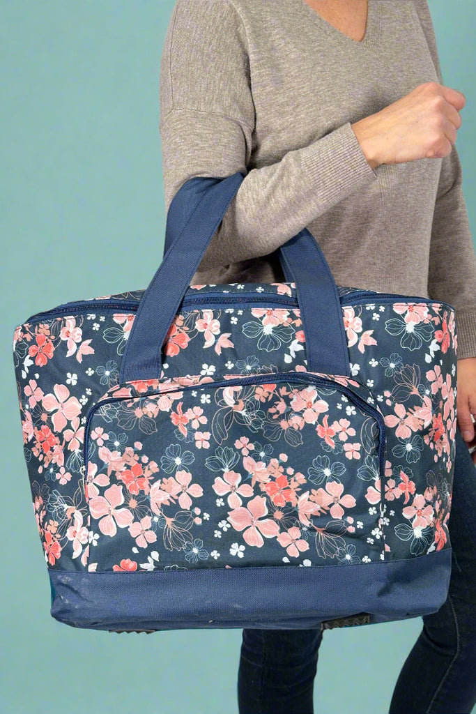 Large soft cooler bag in navy with pink floral print and front zipper pocket.