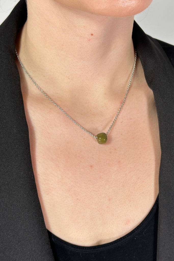 Model is wearing a silver chain collar length necklace with a small green hand rolled bead.