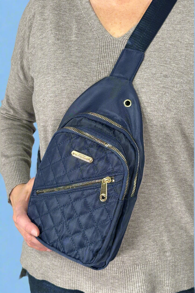 Model is wearing a navy blue nylon sling style bag.