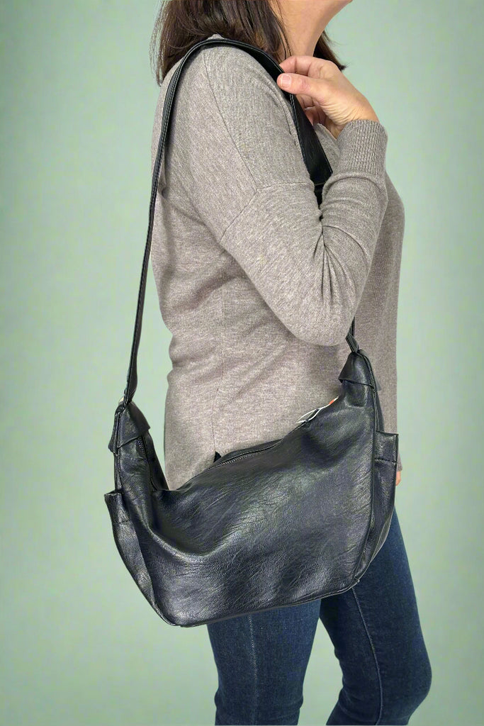 Model is wearing a black slouchy sling crossbody bag.