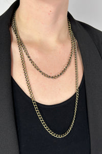 Long brass chain necklace worn as a double layer. 