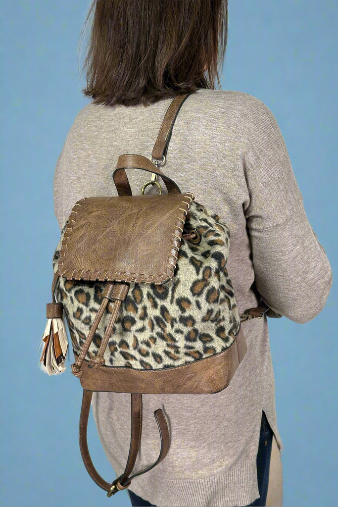 Model is wearing a leopard print mini flap backpack purse. 