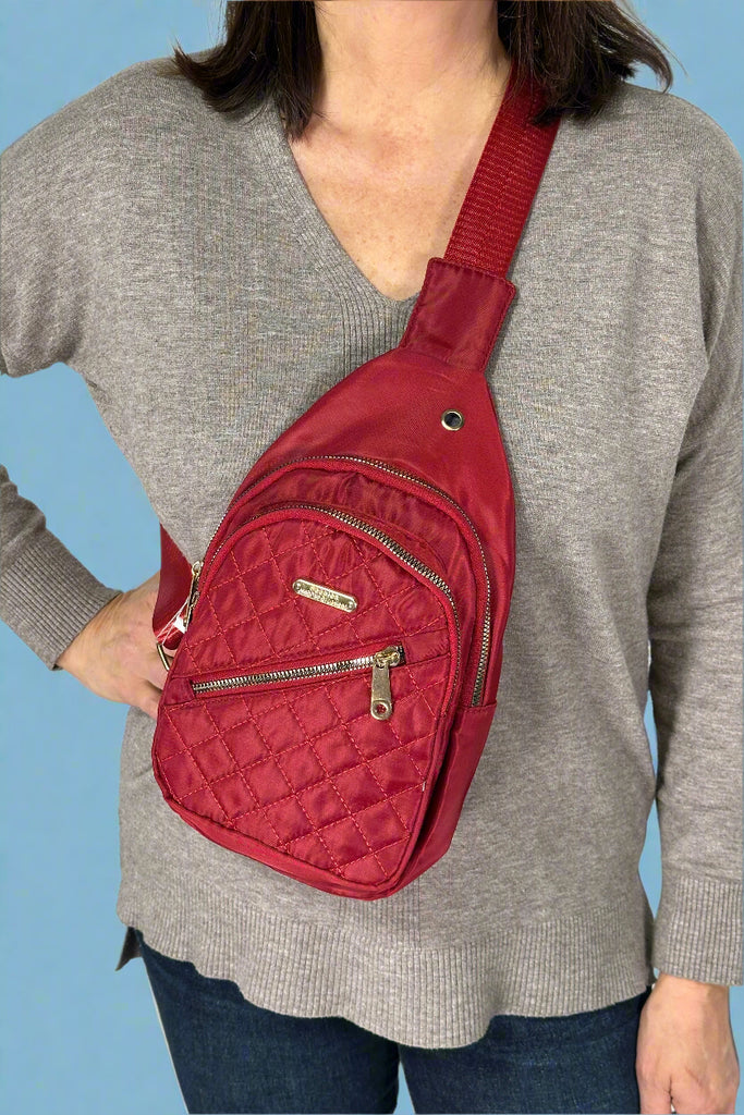 Model is wearing a red blue nylon sling style bag.