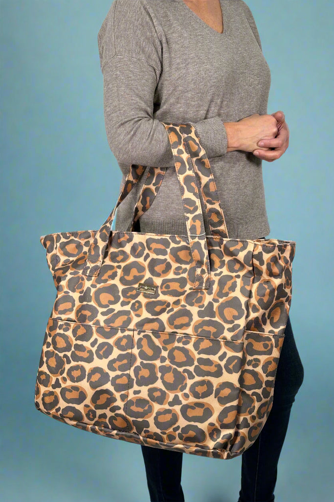 Model is holding a large sized leopard print tote. 