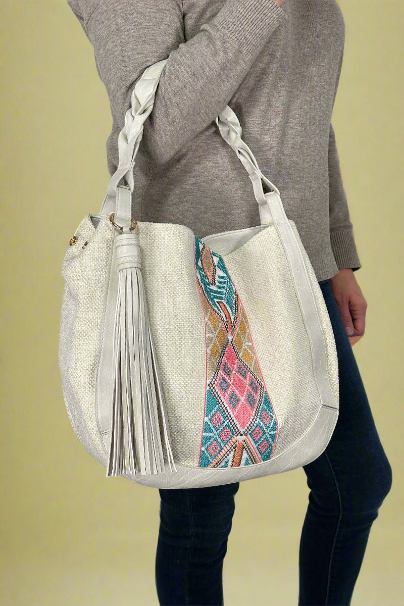 Model is holding a tribal printed saddle bag with a large tassel.
