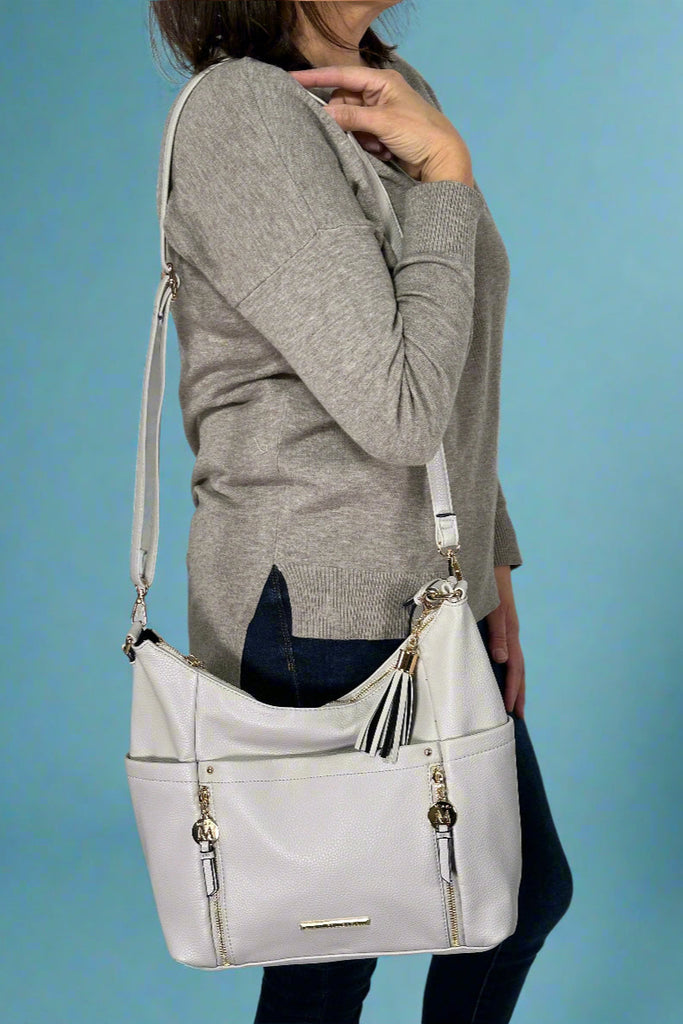 Model is wearing a convertible shoulder bag with tassels.