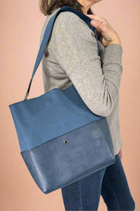 Model is wearing a blue color blocked shoulder tote bag.