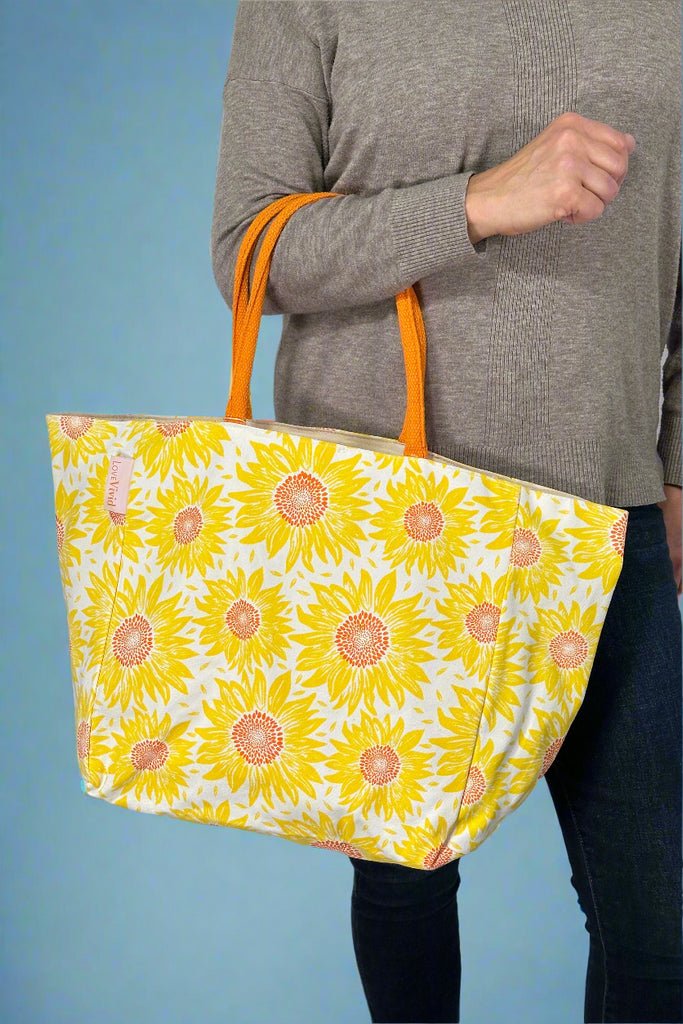 Model is holding a sunflower printed canvas tote bag.