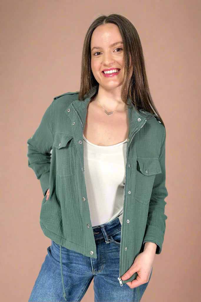 This green utility jacket has a drawstring hem and side pockets. It has a zip and snap closure.