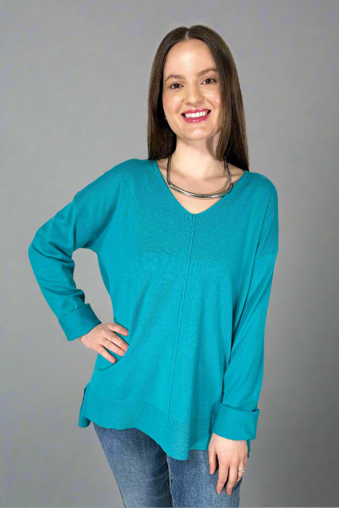 This stretchy, v-neck top is a turquoise color. It has a soft texture, long sleeves, and long length.