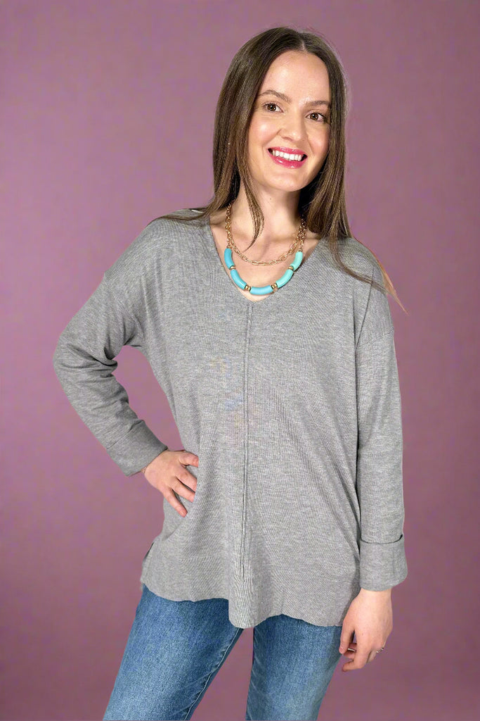 This stretchy, v-neck top is a heather grey color. It has a soft texture, long sleeves, and long length.