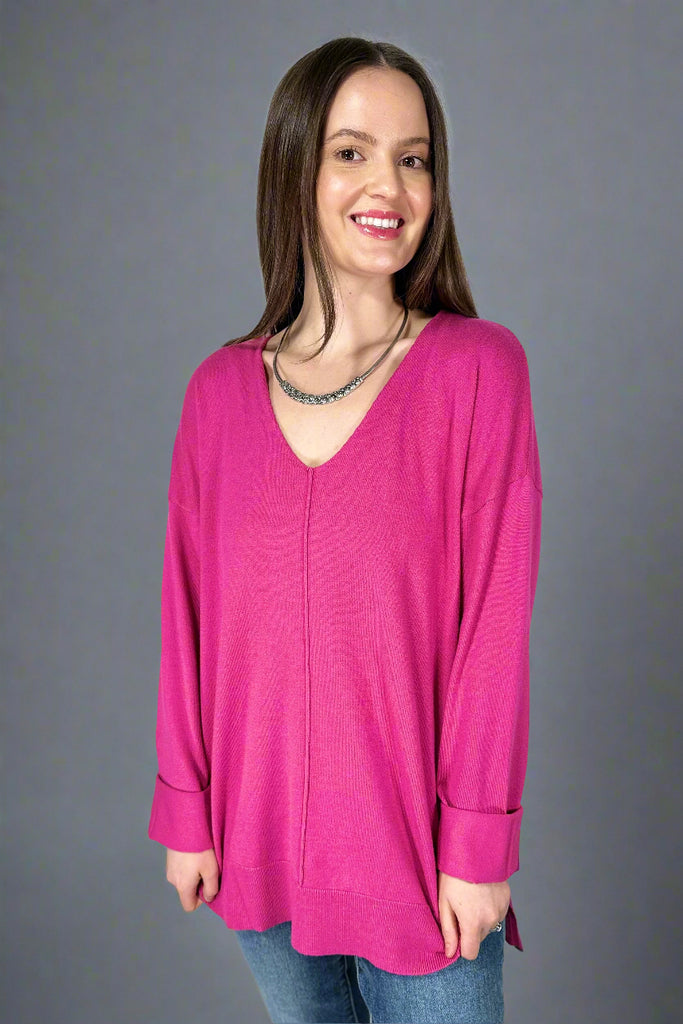 This stretchy, v-neck top is a candy pink color. It has a soft texture, long sleeves, and long length.