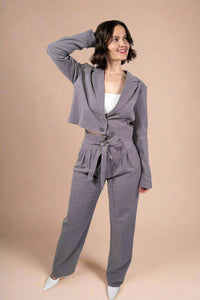 Model is wearing straight leg tie front trousers in grey with subtle pinstripes