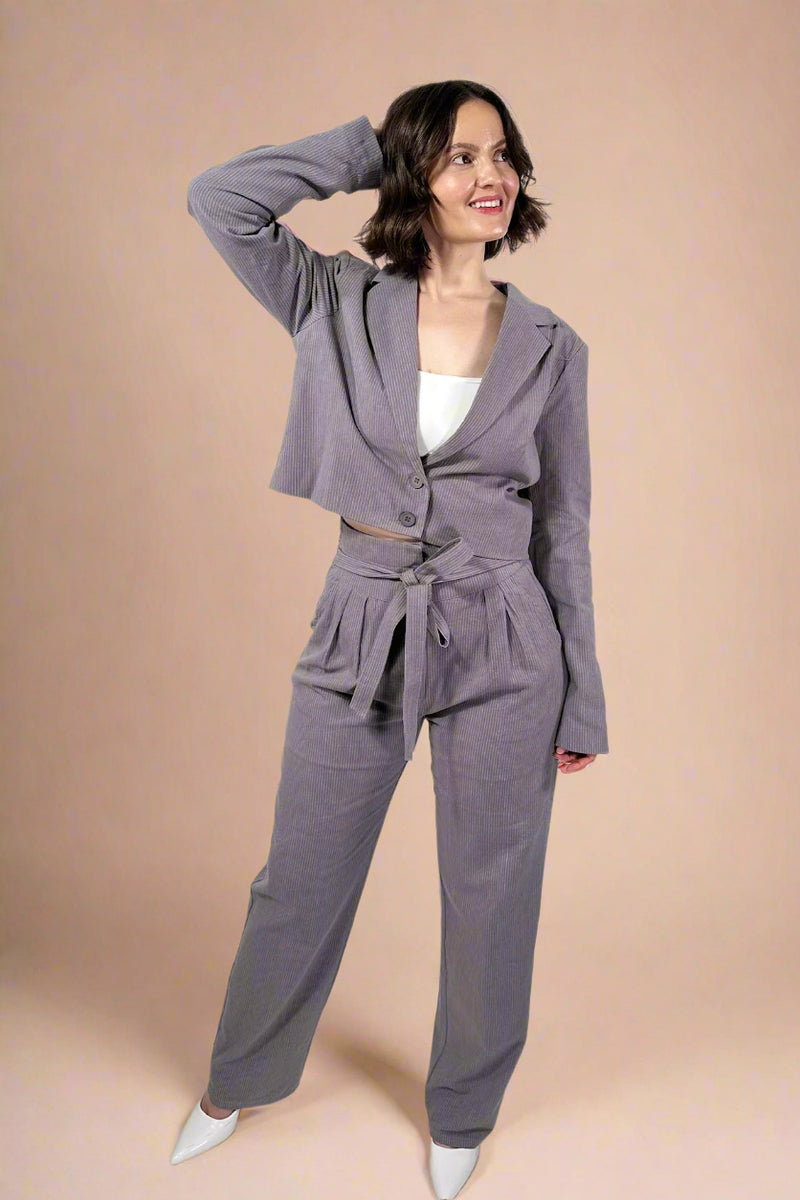 Model is wearing straight leg tie front trousers in grey with subtle pinstripes
