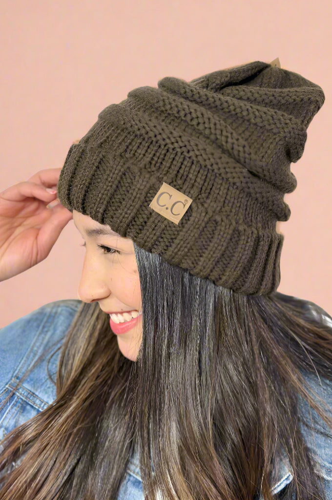 Model is wearing a brown colored slouchy cable knit beanie. 