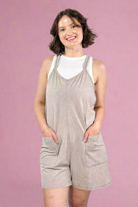 Woman wearing a gray romper against a pink background
