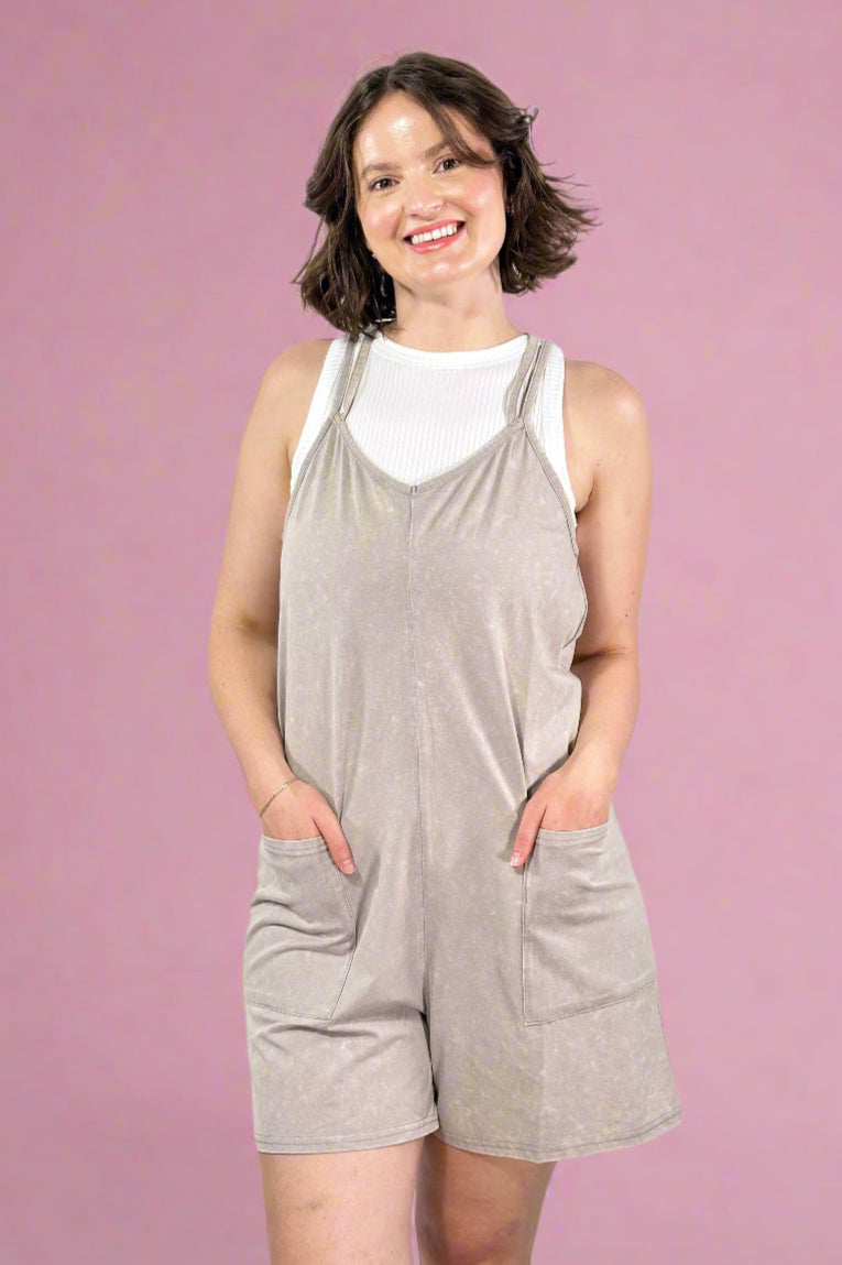 Woman wearing a gray romper against a pink background