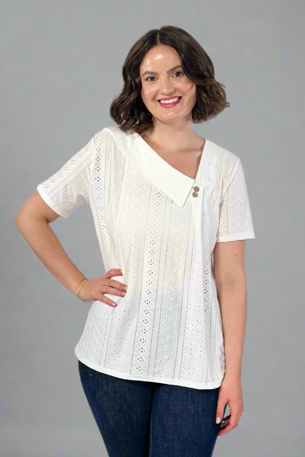 Woman wearing a white blouse with lace details on a plain background