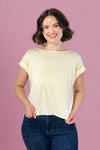 Woman wearing a beige t-shirt and blue jeans against a plain background
